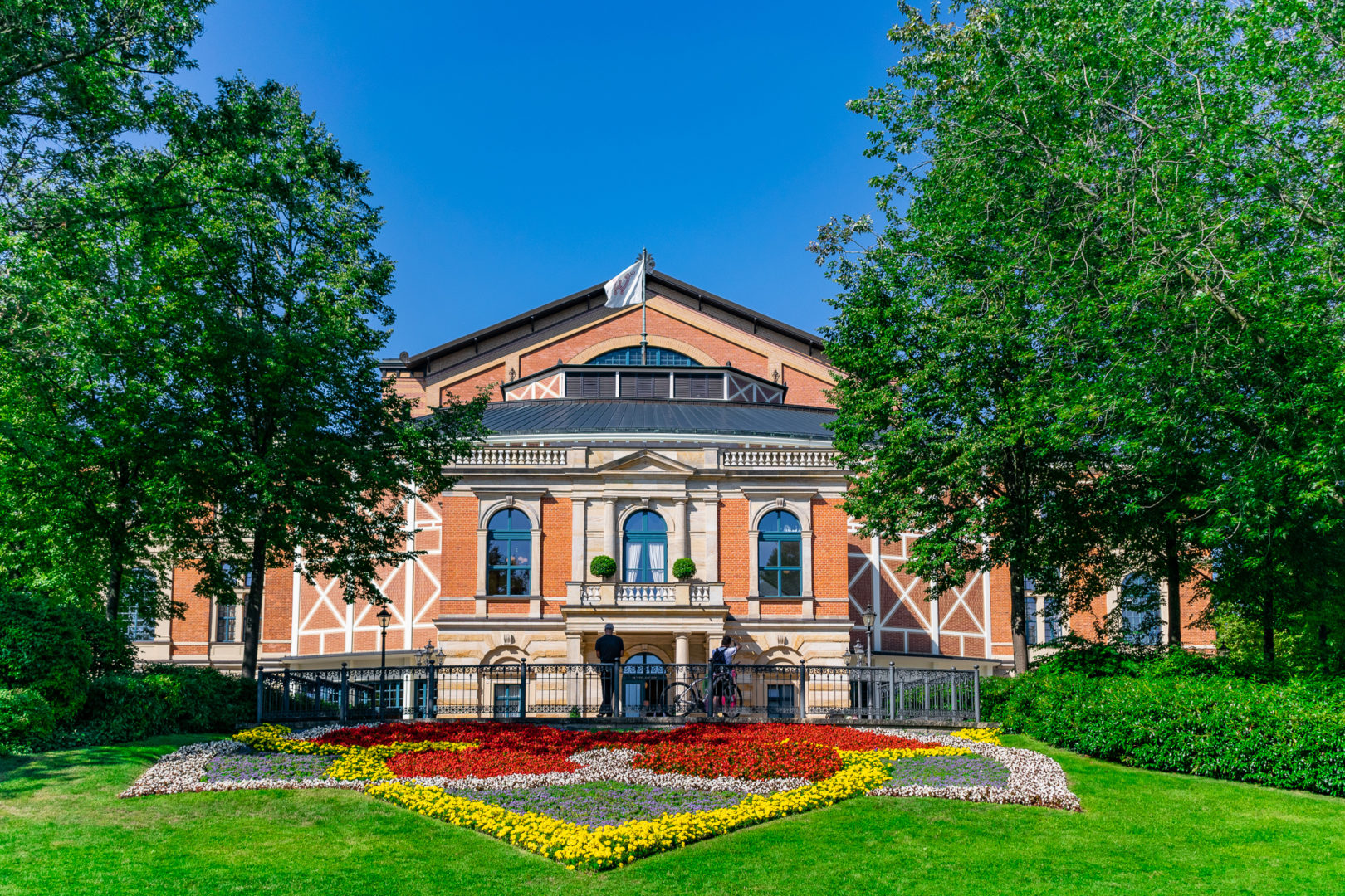 historic opera house surrounded by greenery and colorful flowers